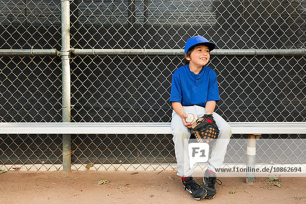Junge sitzt beim Baseball-Training auf der Bank
