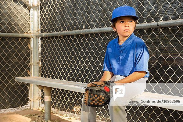 Junge schaut beim Baseball-Training von der Bank aus zu