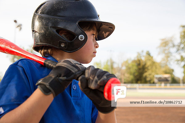 Close up of boy preparing to bat at practise on baseball field