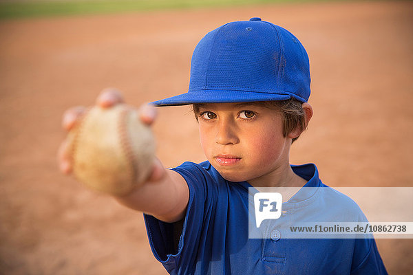 Porträt eines Jungen  der beim Baseball-Training den Ball hochhält