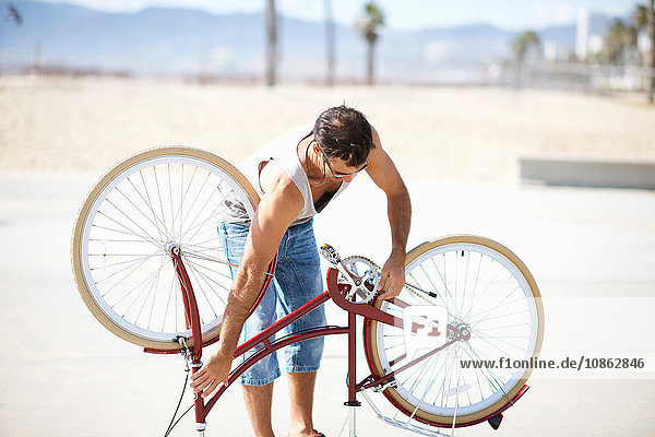 Man repairing bicycle at Venice Beach Los Angeles California USA