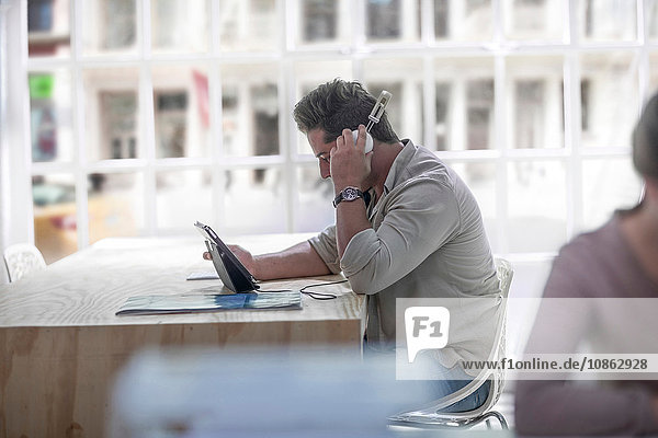 Geschäftsmann benutzt digitales Tablett mit Kopfhörern im Loft-Büro