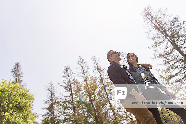 Low angle view of couple strolling wearing sunglasses