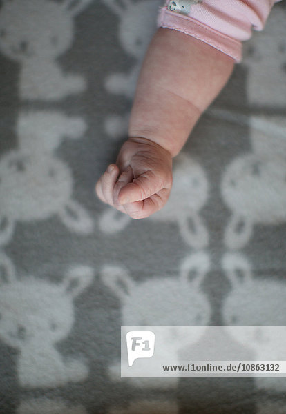 Arm and hand of baby girl on blanket