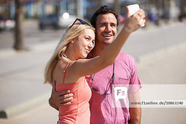 Couple outdoors taking self portrait using smartphone