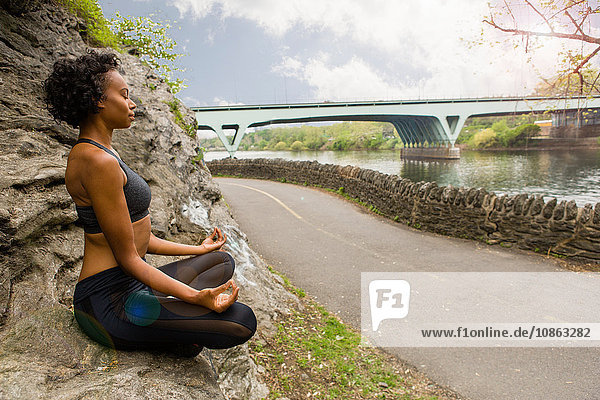 Frau sitzt im Schneidersitz auf einem Felsen und meditiert