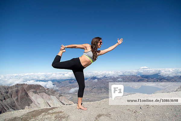 Junge Frau steht auf einem Berggipfel und balanciert auf einem Bein  Mt. St. Helens  Oregon  USA