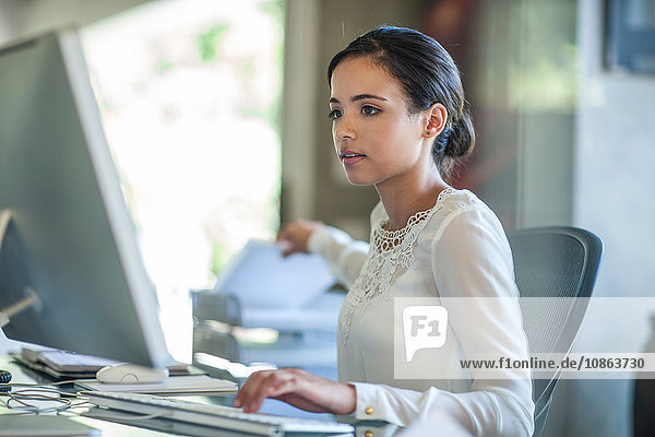 Geschäftsfrau tippt am Desktop-Computer am Büroschreibtisch