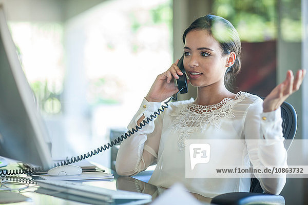 Geschäftsfrau spricht am Büroschreibtisch am Festnetztelefon