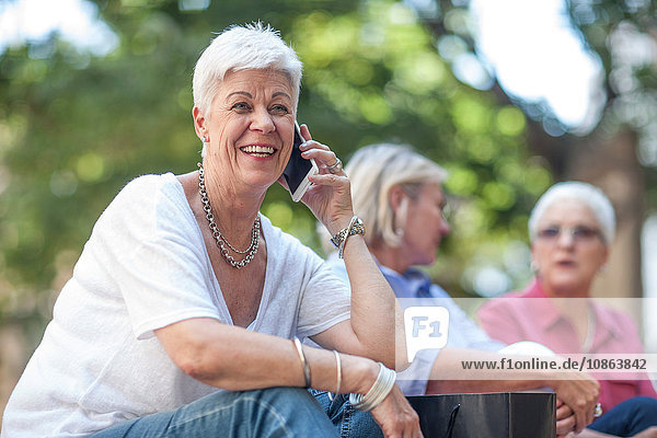 Ältere Frau chattet auf Smartphone in der Stadt