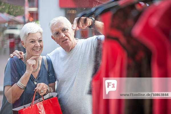 Senior couple shopping for dress in city shop window