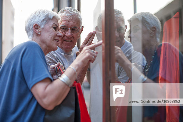 Älteres Ehepaar zeigt auf Stadtschaufenster