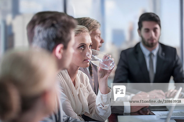 Geschäftsfrau trinkt Wasser am Konferenztisch