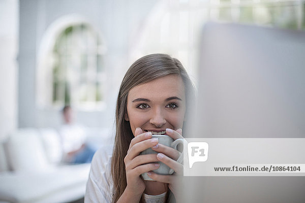 Woman drinking coffee in front of computer
