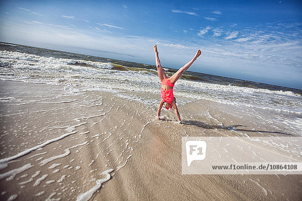 Mädchen macht Handstand am Strand