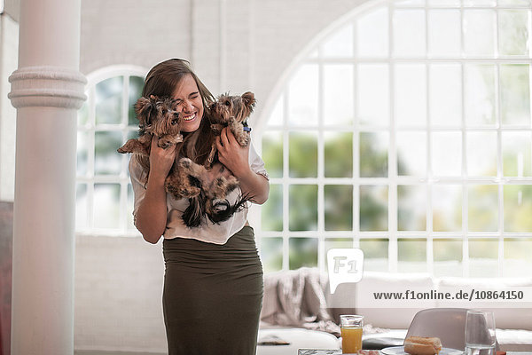 Happy woman hugging pet dogs at home