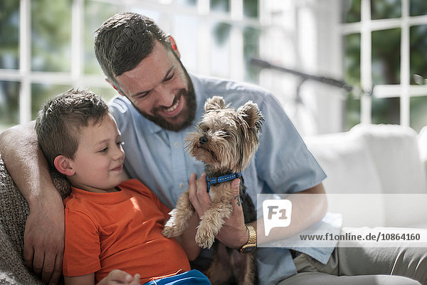 Father and son with pet dog on sofa