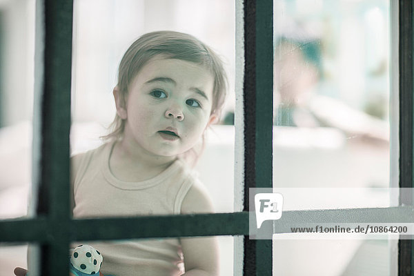 Baby girl looking through window