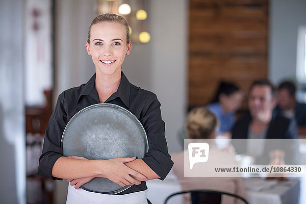 Waitress with serving tray in busy restaurant