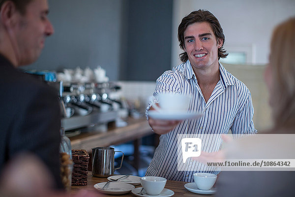 Barista serviert Kaffee an Kunden im Café