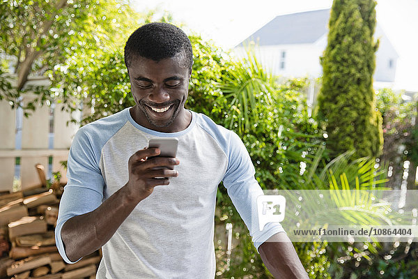 Mann benutzt Mobiltelefon im Garten