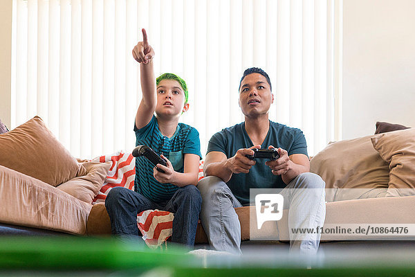 Vater und Sohn spielen Videospiel auf dem Sofa