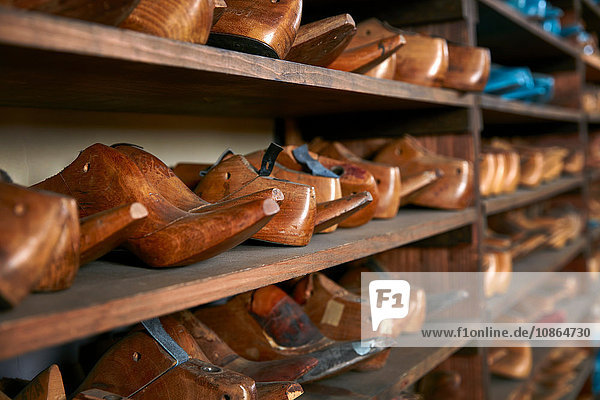 Rows of old wooden shoe lasts on shelves in traditional shoe shop  selective focus
