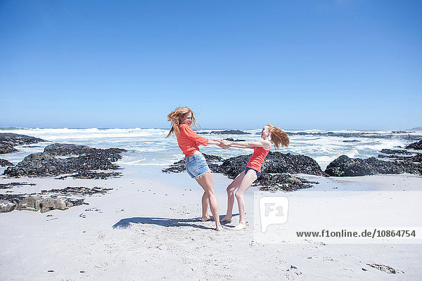 Mädchen und junge Frau halten Händchen und drehen sich am Strand herum  Kapstadt  Südafrika