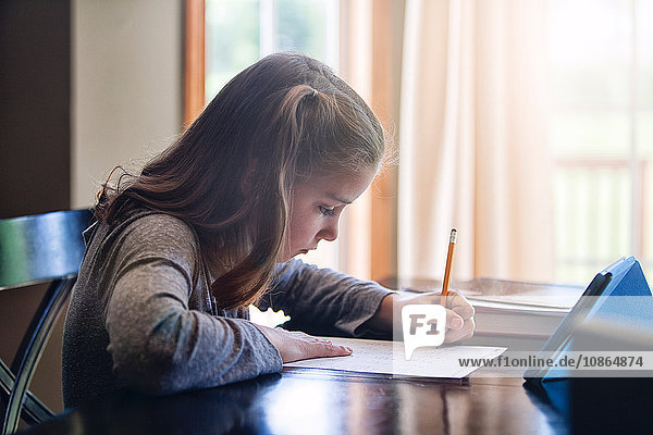 Seitenansicht eines Mädchens beim Schreiben am Schreibtisch