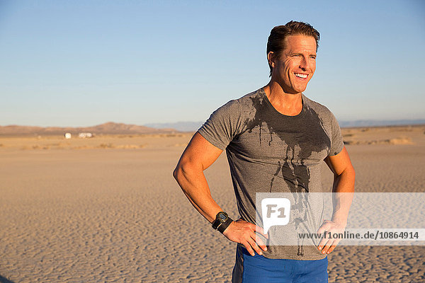 Man training  sweating and taking a break on dry lake bed  El Mirage  California  USA