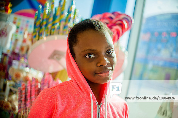 Portrait of teenage girl wearing pink hoody in candy shop  Brooklyn  USA