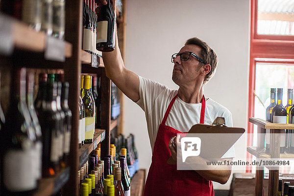Man in wine shop stock taking bottles of wine