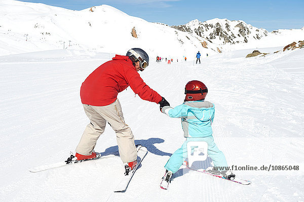Mutter  die dem Sohn das Skifahren beibringt  Rückansicht
