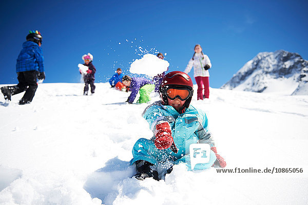 Junge wirft Schneeball  während Freunde hinter ihm spielen