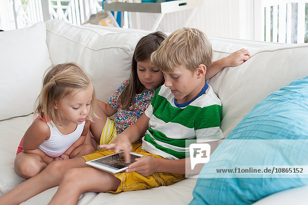 Geschwister auf dem Sofa mit digitalem Tablett