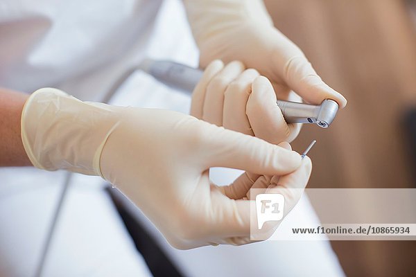 Schrägansicht einer Zahnarzthelferin mit Schutzhandschuhen bei der Vorbereitung der zahnärztlichen Ausrüstung