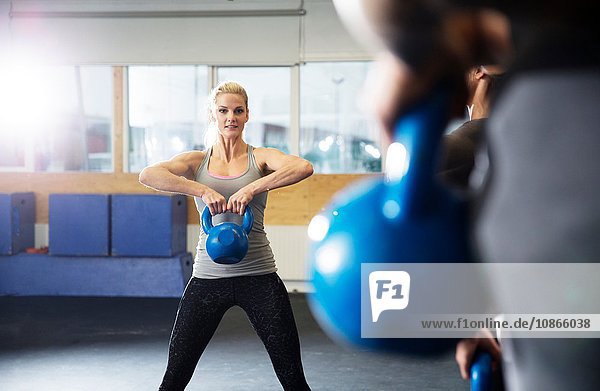 Male and female crossfitters training with kettlebells in gym
