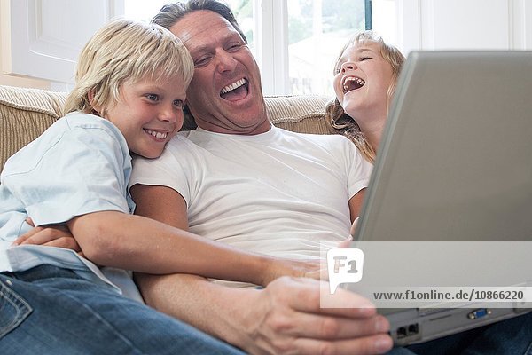 Vater und Kinder lachen  Laptop im Wohnzimmer