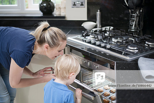Mutter und Sohn schauen in den Ofen  um nach dem Backen zu sehen