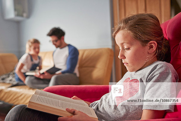 Mädchen  Schwester und Vater konzentrieren sich auf das Lesen von Büchern im Wohnzimmer