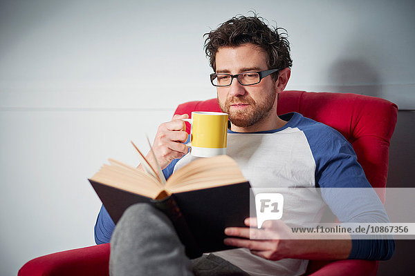 Mid adult man reading book on armchair