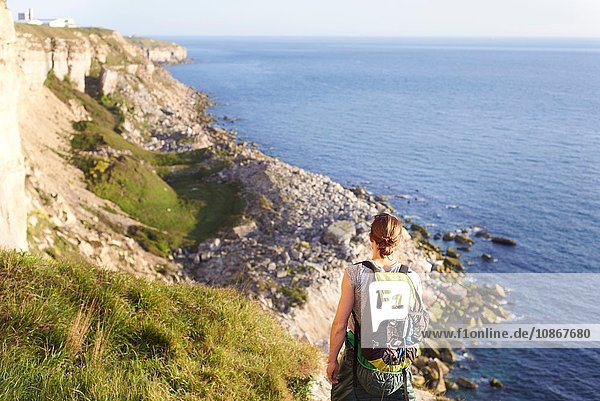 Rückansicht einer Frau mit Rucksack mit Blick auf den Ozean  Portland  UK