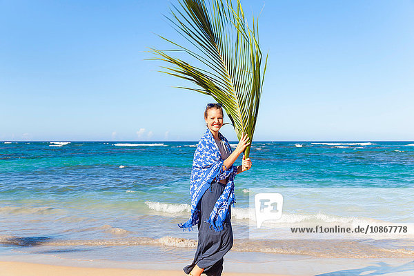 Porträt einer jungen Frau mit Palmenblatt am Strand  Dominikanische Republik  Karibik