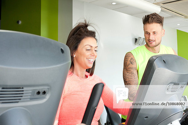 Mann und Frau im Fitnessstudio mit lächelnder Trainingsmaschine