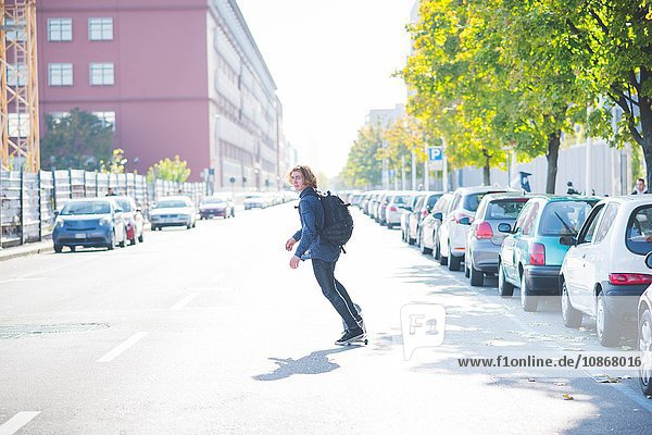 Junge männliche städtische Skateboarder swerve Skateboarding auf der Straße