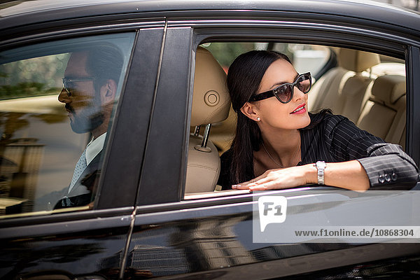 Stylish businesswoman looking back from backseat car window  Dubai  United Arab Emirates