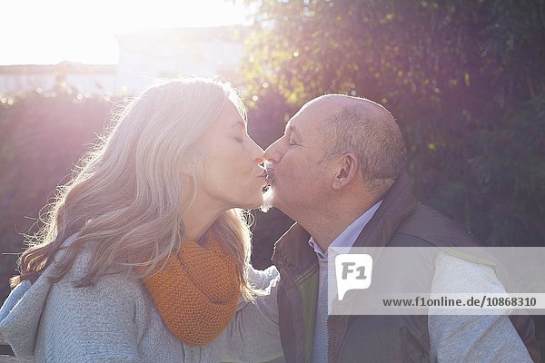 Reifes Paar küsst sich im Sonnenlicht von Angesicht zu Angesicht