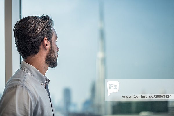 Geschäftsmann blickt durch Fenster mit Blick auf Burj Khalifa Dubai Vereinigte Arabische Emirate