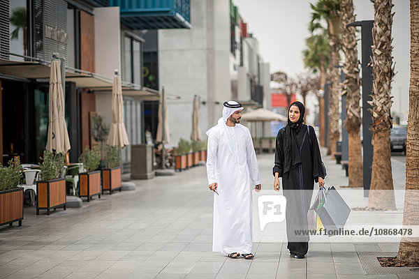 Middle eastern shopping couple wearing traditional clothing carrying shopping bags  Dubai  United Arab Emirates
