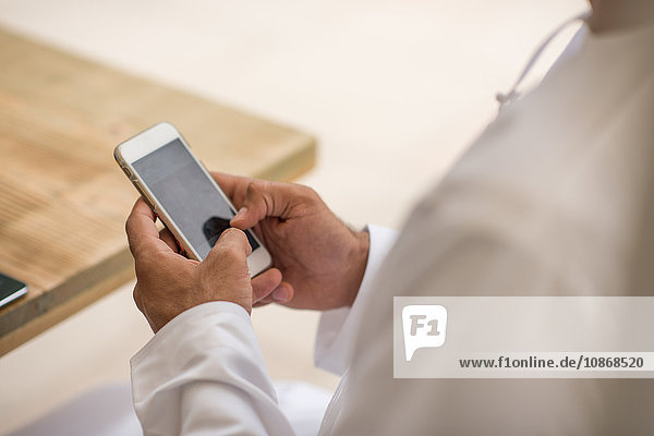 Nahaufnahme der Hände eines Mannes aus dem Nahen Osten mit einem Smartphone-Touchscreen in einem Café in Dubai  Vereinigte Arabische Emirate